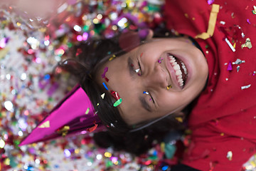 Image showing kid blowing confetti while lying on the floor