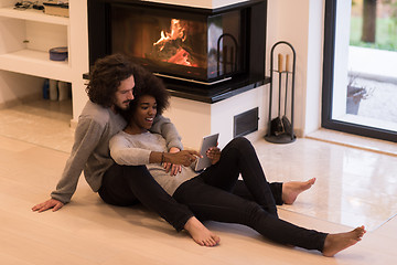 Image showing multiethnic couple using tablet computer on the floor