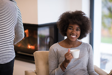 Image showing black woman reading book  in front of fireplace