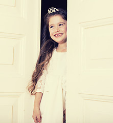 Image showing little cute girl at home, opening door well-dressed in white dre