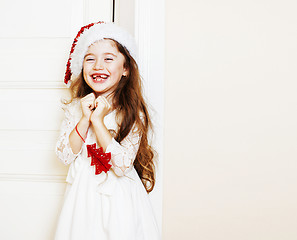 Image showing little cute girl in santas red hat waiting for Christmas gifts. 