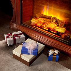 Image showing Christmas gifts boxes near fireplace