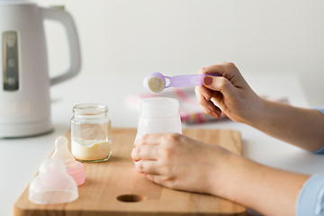 Image showing hands with bottle and scoop making formula milk