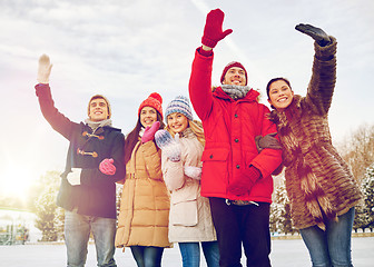 Image showing happy friends waving hands outdoors