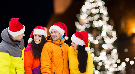 Image showing friends in santa hats and ski suits at christmas