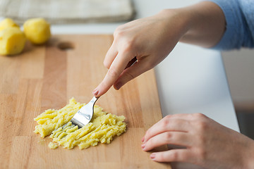 Image showing hand with fork making mashed potato on board