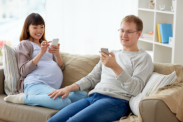 Image showing husband and pregnant wife with smartphone at home