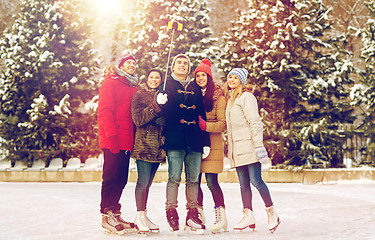 Image showing happy friends with smartphone on ice skating rink