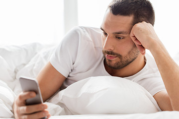 Image showing close up of man with smartphone in bed in morning