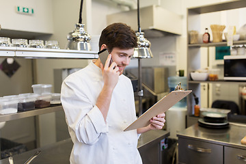 Image showing chef cook calling on smartphone at restaurant kitchen