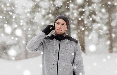 Image showing sports man with earphones in winter forest