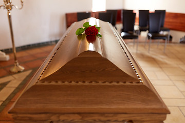 Image showing red rose flower on wooden coffin in church