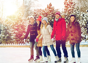 Image showing happy friends ice skating on rink outdoors