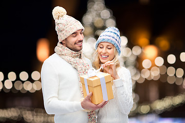 Image showing happy couple with christmas gift over night lights