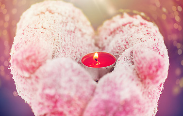 Image showing close up of hands in winter mittens holding candle