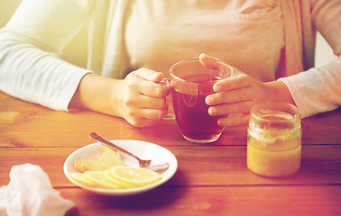 Image showing close up of woman adding lemon to tea cup