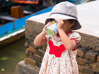 Image showing Small girl drinking sweetened, condensed milk
