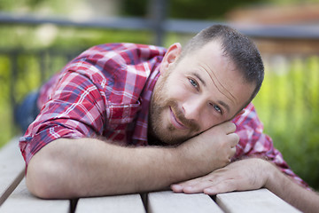 Image showing bearded handsome man lying on a bench