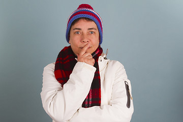 Image showing Woman in winter clothes puts finger on her mouth