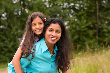 Image showing Smiling mother giving piggyback to daughter