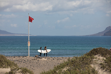 Image showing The red flag weighs in the wind at Surfers Beach Famara on Lanza