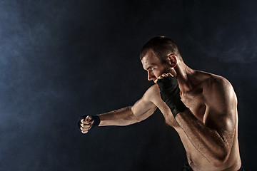 Image showing The young man kickboxing on black