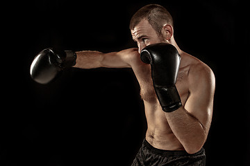 Image showing The young man kickboxing on black