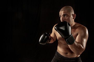 Image showing The young man kickboxing on black