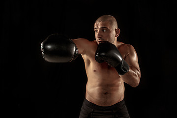 Image showing The young man kickboxing on black