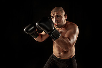 Image showing The young man kickboxing on black