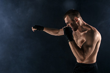 Image showing The young man kickboxing on black