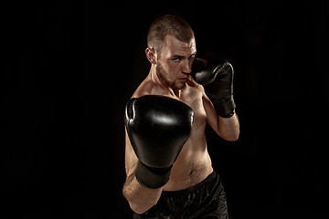 Image showing The young man kickboxing on black