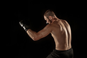 Image showing The young man kickboxing on black