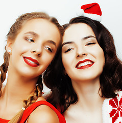 Image showing young pretty happy smiling blond and brunette woman girlfriends on christmas in santas red hat and holiday decorated plaid, lifestyle people concept