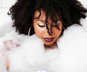 Image showing young afro-american teen girl laying in bath with foam, wearing 