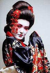 Image showing young pretty geisha in kimono with sakura and red decoration design on white background