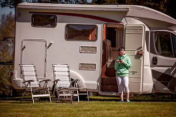 Image showing Woman is standing with a mug of coffee near the camper RV.