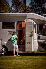 Image showing Woman is standing with a mug of coffee near the camper RV.