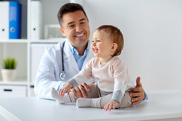 Image showing happy doctor or pediatrician with baby at clinic