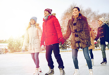 Image showing happy friends ice skating on rink outdoors