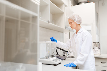 Image showing woman with sulphuric acid and scale at laboratory