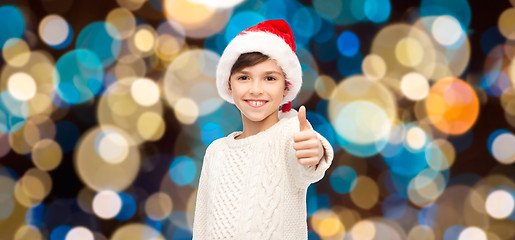 Image showing boy in santa hat showing thumbs up at christmas