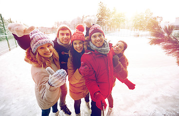 Image showing happy friends with smartphone on ice skating rink