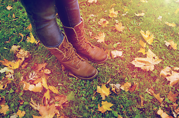 Image showing female feet in boots and autumn leaves on grass