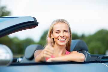 Image showing happy young woman in convertible car thumbs up