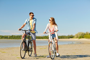 Image showing happy young couple riding bicycles at seaside