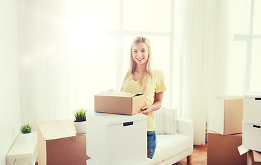 Image showing smiling young woman with cardboard box at home