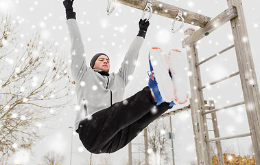 Image showing young man exercising on horizontal bar in winter