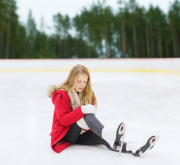 Image showing young woman with knee injury on skating rink