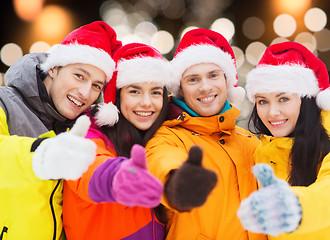 Image showing happy friends in santa hats and ski suits outdoors